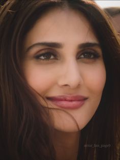 a close up of a woman with long brown hair and eyeshade smiling at the camera