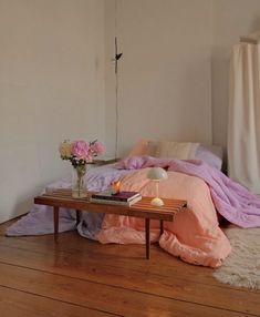 a room with a bed, table and flowers on the floor