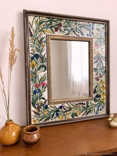 a mirror sitting on top of a wooden table next to vases and a plant