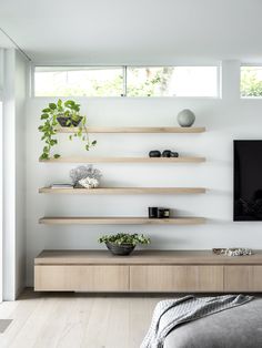 a living room filled with lots of shelves next to a tv mounted on a wall