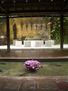 a vase with flowers sitting on the ground in front of a wall and water fountain