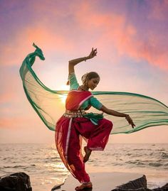 a woman dancing on the beach at sunset