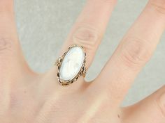 "This vintage ring is crafted in wonderful tones of yellow and creamy white! 14K yellow gold comprises the frame, while the cameo at the center is carved from pale, barely blush pink conch shell. This unusual piece is timeless, likely made in Italy in the mid-1900's Metal: 14K Yellow Gold Gem: Pink Shell Cameo Gem Measurements: 19.1 x 9.2 mm, Oval Ring Size: 5.75 Marks: \"14K\" Stamped on the inside band SKU #: 0CLA3D-N Each piece has been identified and graded by a Graduate Gemologist who has b Gold Oval Cameo Rings, White Oval Heirloom Signet Ring, Victorian White 14k Gold Rings, Heirloom White Oval Signet Ring, Heirloom White Oval Engraved Ring, Heirloom White Engraved Oval Ring, White Signet Ring For Wedding, Heirloom Style White Engraved Promise Ring, White Heirloom Engraved Promise Ring