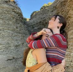 two women hugging each other in the middle of an old stone tunnel, one woman has her eyes closed and she is wearing a striped sweater