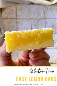 a hand holding up a bar of gluten - free easy lemon bars