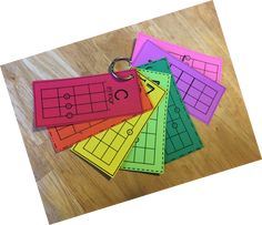 four different colored paper tags with numbers on them sitting on a wooden surface next to a pair of scissors