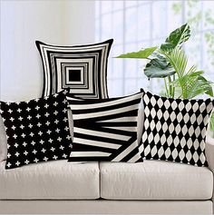 four black and white pillows sitting on top of a couch next to a potted plant