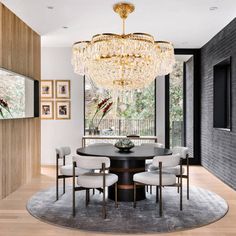 a dining room with a chandelier hanging from the ceiling and chairs around it