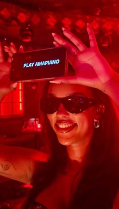 a woman wearing sunglasses and holding up a cell phone to her face with the word play amapiano on it