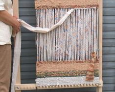 a man standing next to a weaving machine with a white scarf hanging from it's side