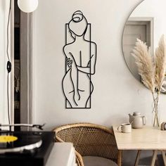 a room with a table, chair and mirror on the wall that has a drawing of a woman holding a baby