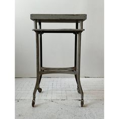 an old wooden table sitting on top of a white tiled floor next to a wall