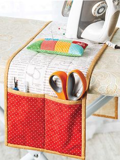 an ironing board with scissors and other sewing supplies in the pocket on top of it