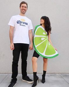 a man standing next to a woman holding a slice of lime in front of her