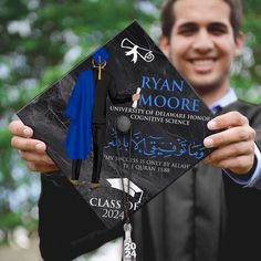 a man holding up a graduation cap and gown