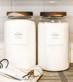 two jars with labels on them sitting on a counter next to a pair of scissors