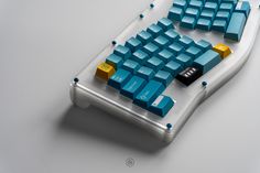 a blue and yellow computer keyboard sitting on top of a white table with lots of keys