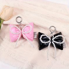 two black and pink bows with pearls on them are sitting next to a tulip