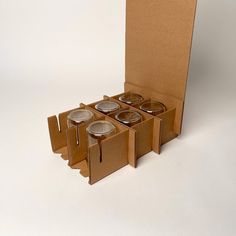 a cardboard box with four candles in it sitting on a table next to each other