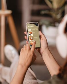 a woman is holding her cell phone while sitting on the couch and looking at it