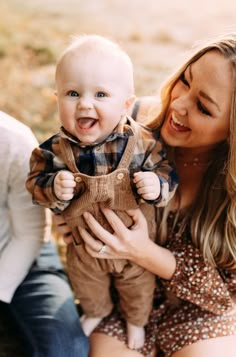 a woman holding a baby and smiling at the camera