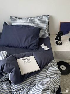 a bed with blue and white striped comforter next to a night stand on the floor