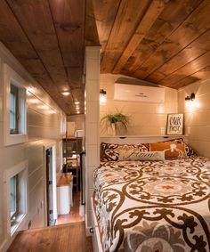 a bed in a room with wooden ceiling and white walls, along with two windows