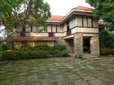 a house with stone walkways and trees in the background