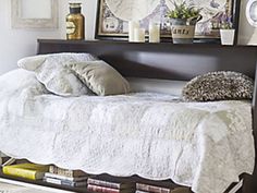 a bed that has some books on the bottom shelf in front of it and a mirror above it