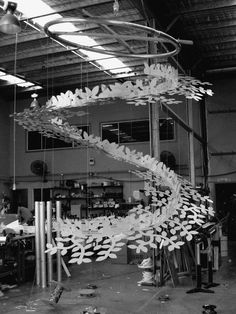 an artistic sculpture made out of paper leaves in a building with workers working on it