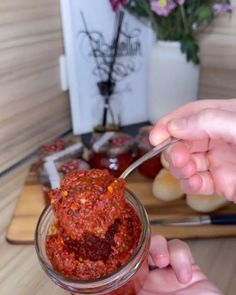 a person holding a spoon full of food in front of some other items on a table