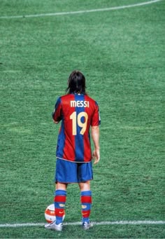 a man standing on top of a field next to a soccer ball in front of him
