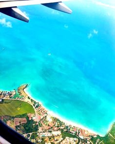 the view from an airplane window looking down on a tropical island and blue water below