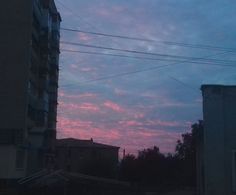 the sky is pink and blue as it sets in the distance with buildings on either side