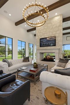 a living room with couches, chairs and a tv mounted on the wall above a fireplace