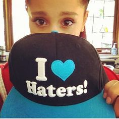 a young boy holding up a hat with i love haters written on it