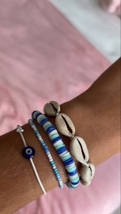 a woman's arm with three bracelets on it and two seashells