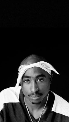 a black and white photo of a man with a bandana on his head looking at the camera