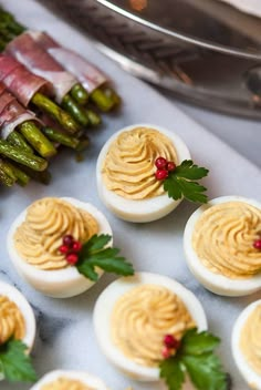 deviled eggs with mustard spread and green asparagus on a tray next to other appetizers