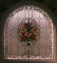 a stained glass window with flowers in the center and an ornate frame around it,