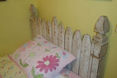 a bed with pink and green flowers on the pillow cover, next to a yellow wall