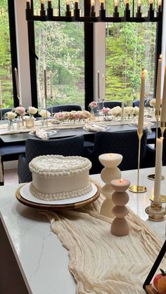 a white cake sitting on top of a table next to candles and plates filled with fruit