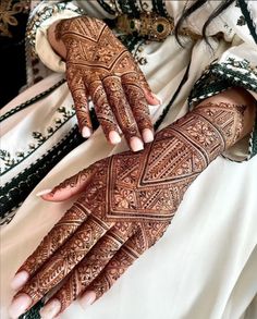 a woman's hands with hennap on her arm and hand, showing the intricate