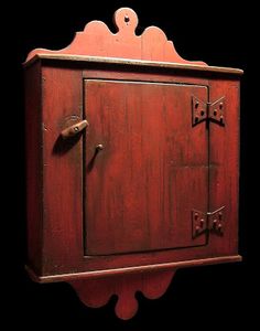 an old wooden cabinet with two doors and knobs on the front, against a black background