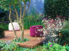 a wooden deck surrounded by plants and flowers