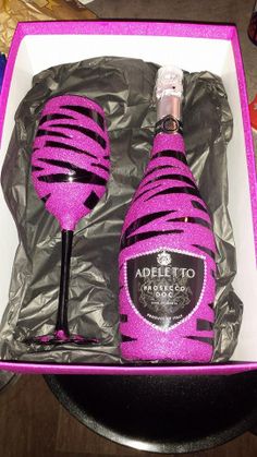 two wine glasses in a box with pink and black stripes on the top one is empty