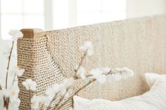 a close up of a bed with white flowers on the headboard and pillows in front of it