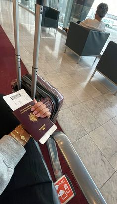 a woman is sitting on the floor with her luggage and holding a passport in her hand