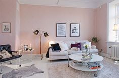 a living room with white furniture and pink walls