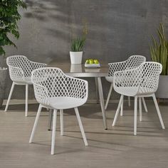 four white chairs and a table with fruit on it